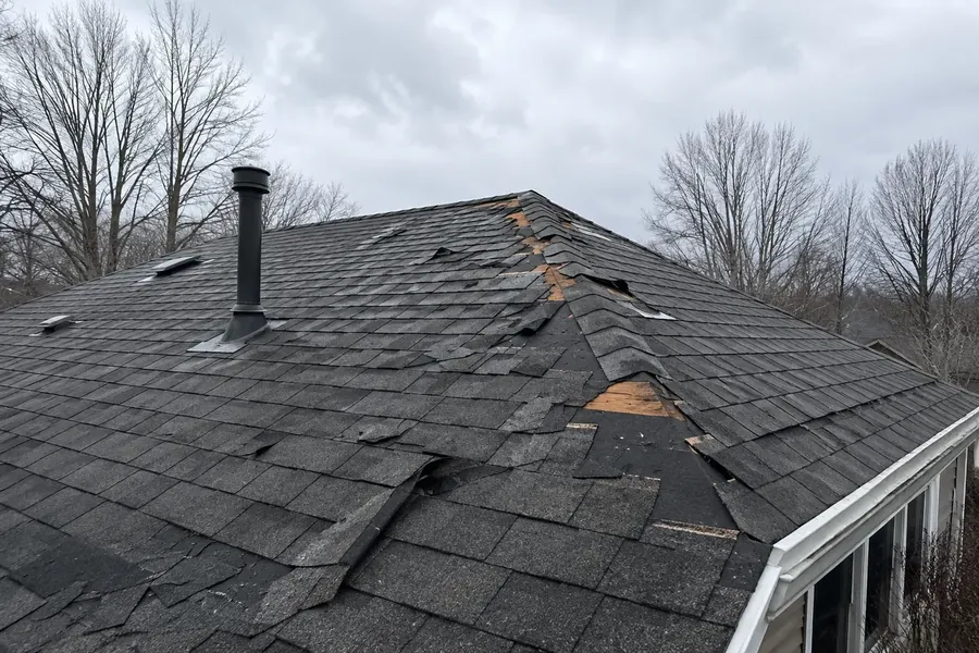 Roof with shingles lifted and torn away after a windstorm