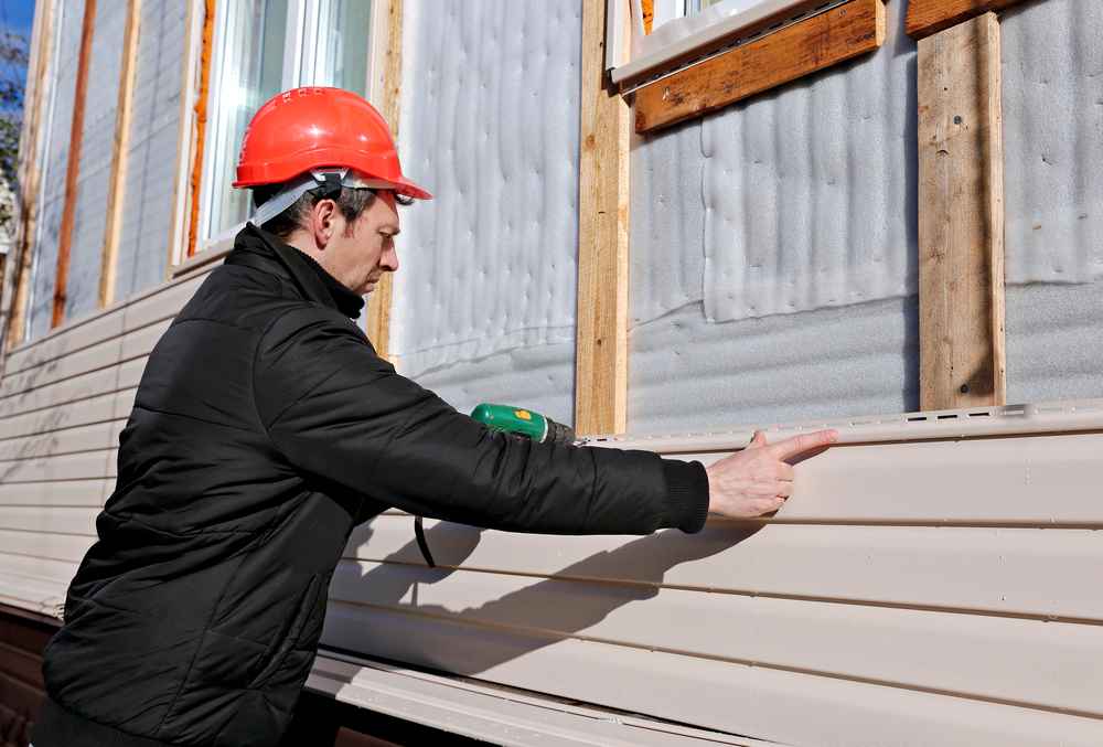 Professional siding contractor installing durable exterior siding on residential home